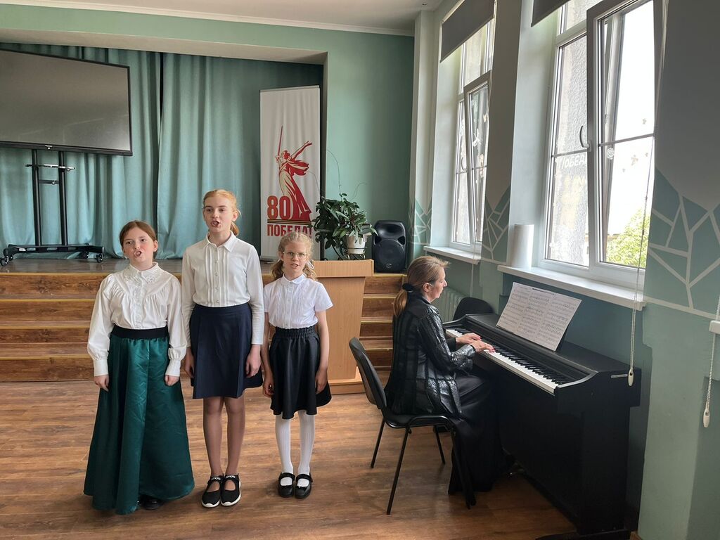 Девочки поют, учитель за роялем